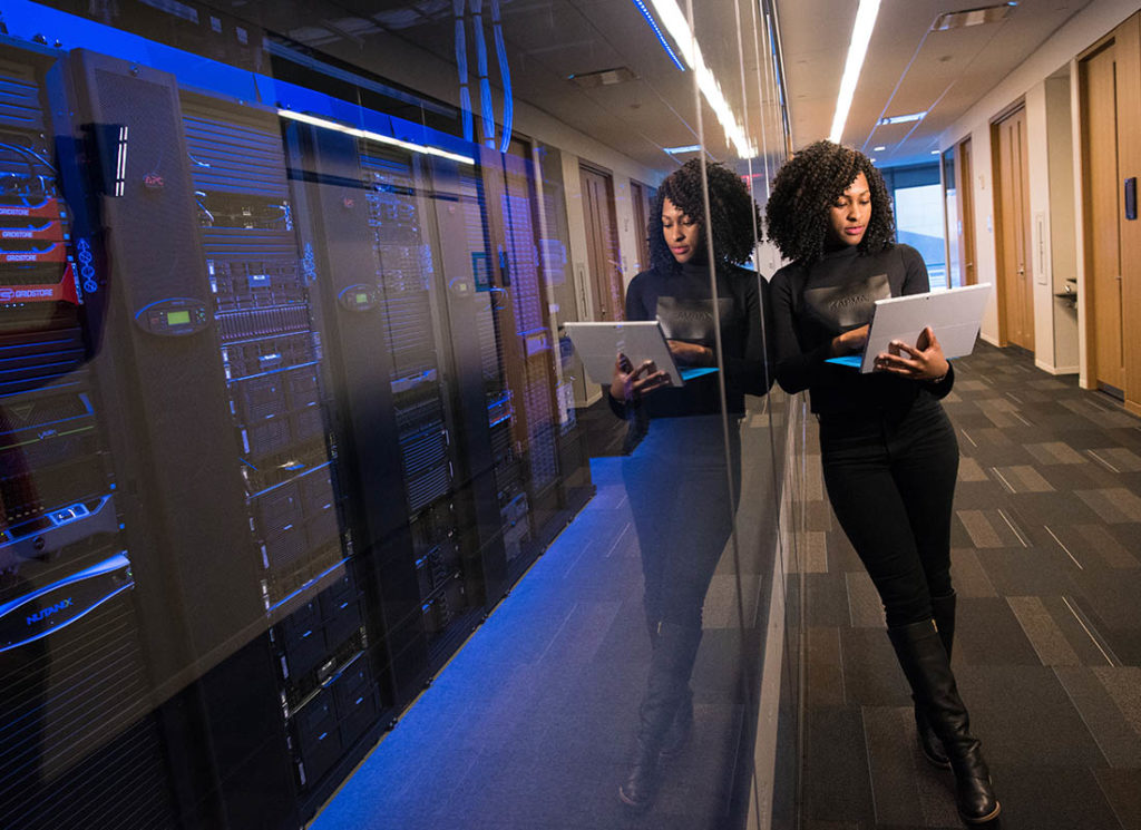 Software Implementation & Optimization - Woman Holding Laptop Near Servers at an Office